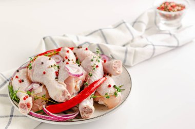 Çiğ tavuk budu, beyaz arka planda otlar ve baharatlar. Boşluğu kopyala.