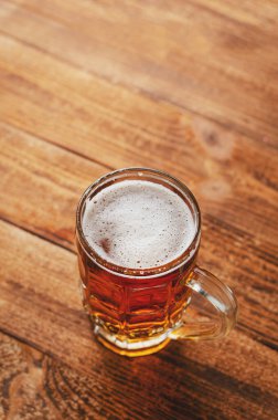 Ahşap arka planda bir bardak bira. Dikey, boşluğu kopyala. Alkolik içecekler