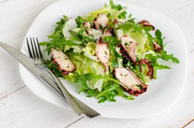 Deniz ürünleri aperatifi. Beyaz tabakta ahtapot salatası. Akdeniz lezzeti işte. Seçici odak, kapat