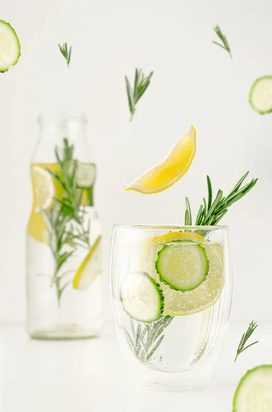 Food levitation concept. Detox water or lemonade with lemon, cucumber and rosemary in a glass on white background. Weight loss and healthy lifestyle.