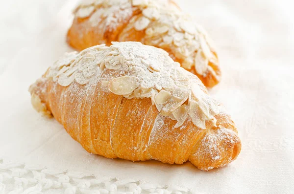Breakfast bakery, croissant with powdered sugar and almond flakes on white background. Close up.
