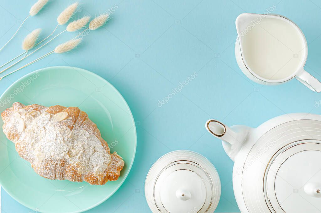 Morning table. Fresh croissants on turquoise plates and milk on pastel blue background. Top view, copy space.