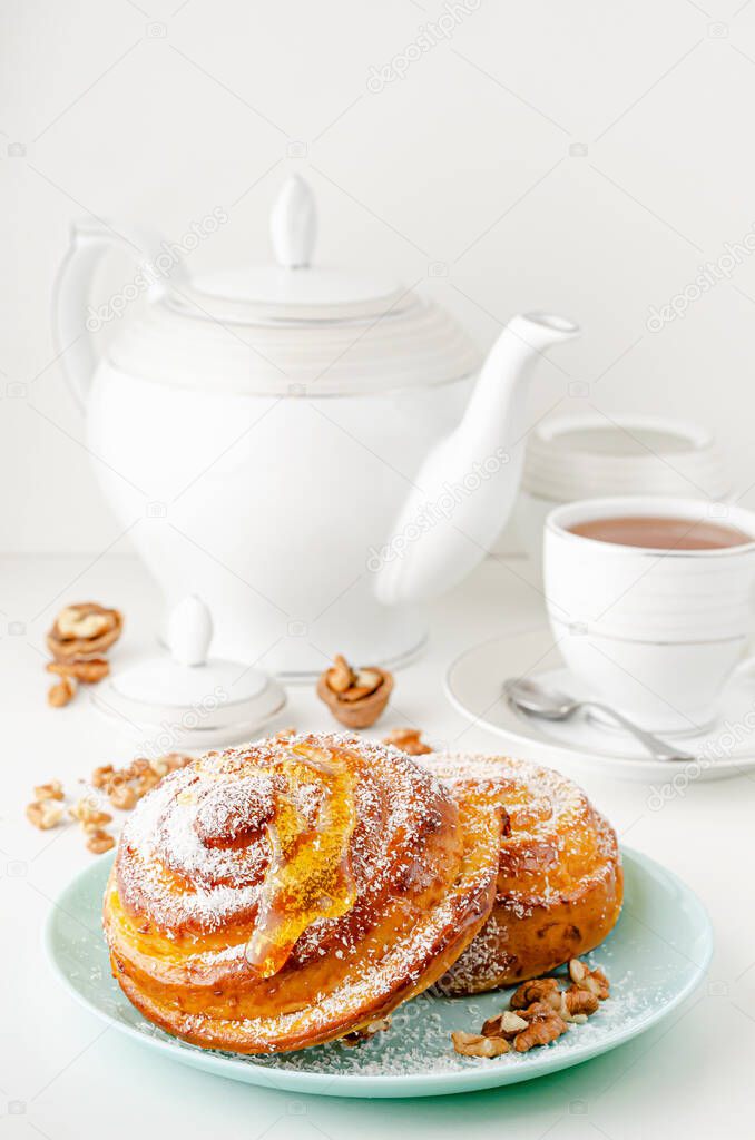 Homemade bakery. Sweet buns with honey, walnuts and grated coconut on white background. Breakfast table concept.