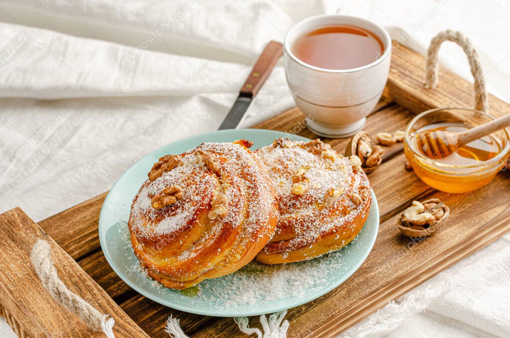 Traditional Swedish bakery or kanelbulle with walnuts on wooden tray. Breakfast or snack concept. Close up