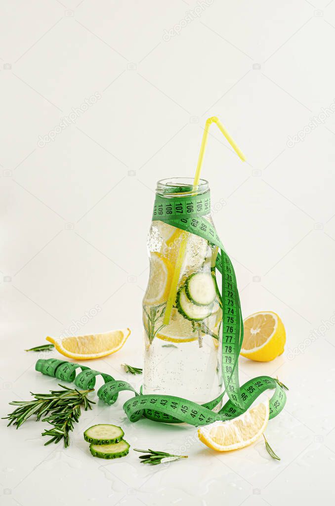 Measuring tape and a bottle of detox water with lemon,cucumber and rosemary. Weight loss and healthy lifestyle concept