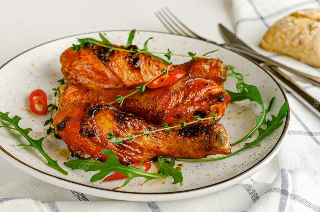 Roasted spicy chicken legs or drumsticks on a white dish. Delicious dinner or lunch concept.