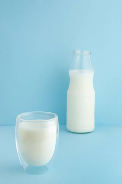Mavi arka planda sütlü duble alttaki bardak. Uzayı kopyala Sağlıklı yaşam tarzı kavramı. Laktozsuz.