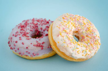 Pastel mavi arka planda geleneksel Amerikan donutları. Kapat..