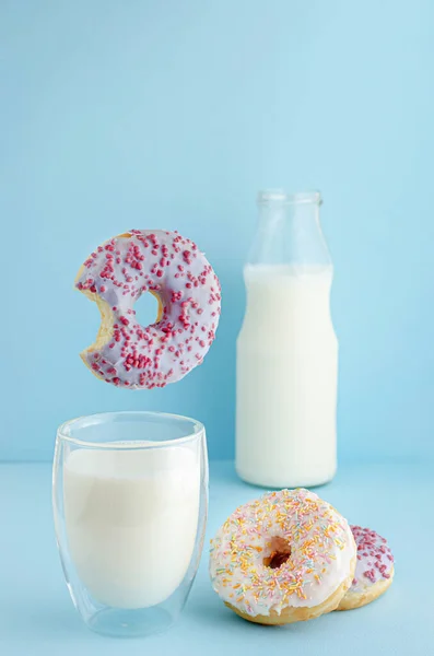 Flying food concept. Delicious breakfast with glass of milk and doughnuts on pastel blue background with copy space.
