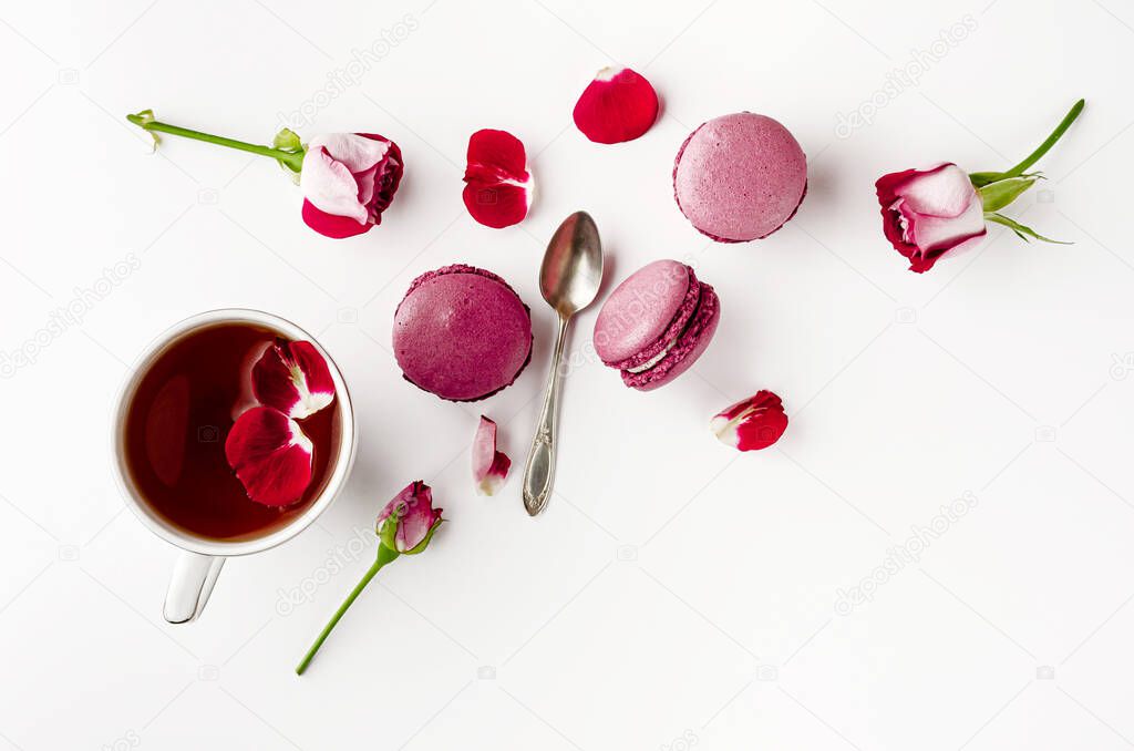 Breakfast tea on white table with roses and macarons. Vallentines day, womens day and romance concept. Flat lay, top down. Copy space