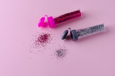 Pastel pembe arka planda pembe ve gümüş parıltılı şişeler. Düz yat, boşluğu kopyala.