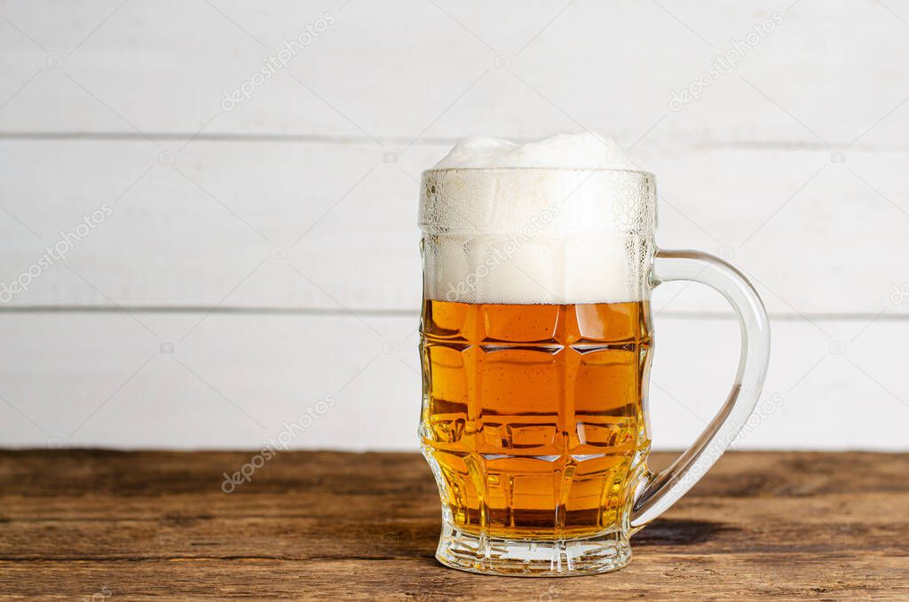 Full glass of blonde beer on white wooden backgroud. Copy space