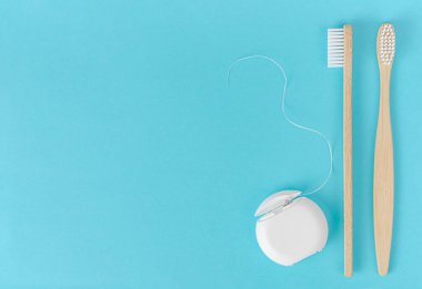 Bambu diş fırçası ve mavi arka planda diş ipi. Diş sağlığı konsepti