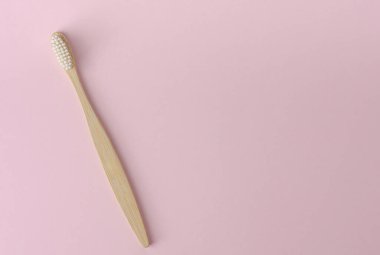 Pastel pembe arka planda ekolojik bambu diş fırçası. Üst görünüm, alanı kopyala