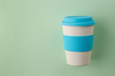 Pastel yeşil arka planda silikon tutacağı olan yeniden kullanılabilir plastik ücretsiz bambu bardağı. Üst görünüm, boşluğu kopyala. Sıfır atık.