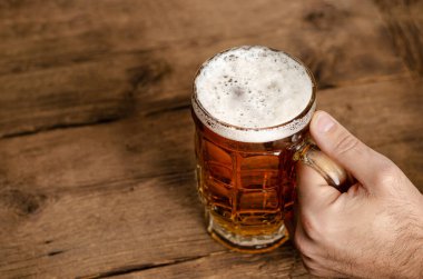 Erkek eli dolu bir bardak sarışın birası tutuyor. Zevk konsepti. Boşluğu kopyala