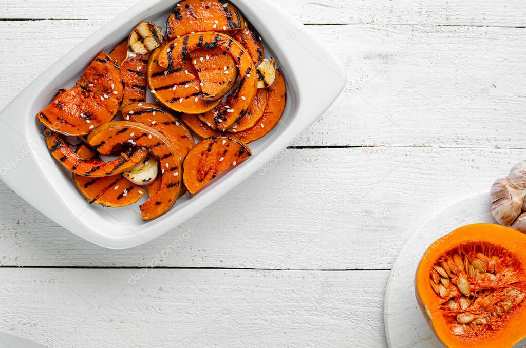 Grilled butternut pumpking slices on white wooden background. Healthy organic dieting food. Top view, copy space
