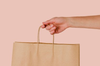Pembe arka planda elinde kağıt torba tutan bir kadın. Alışveriş ve satış kavramı