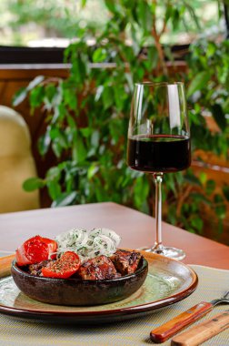 Geleneksel Gürcü eti domatesli ve tuzlanmış soğanlı şiş üzerinde kırsal kasede servis edilir. Restoran menüsü kavramı