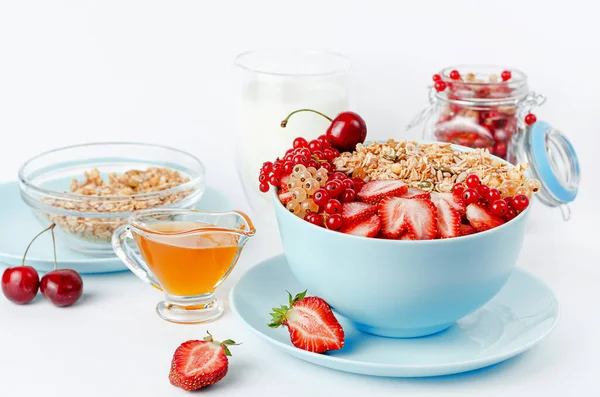Healthy breakfast of granola bowl with fresh strawberries, currant and honey on white background.