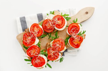 Beyaz arka planda mozzarella peynirli, domatesli ve roka aromalı sandviç. Üst manzara, İtalyan mutfağı.