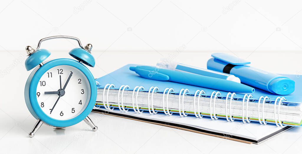 Back to school concept. Blue clock and supplies on white background.