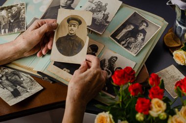 Cherkasy / Ukrayna - 12 Aralık 2019: kadın el ele tutuşması ve büyükbabasının eski fotoğrafı. Fotoğraflı klasik fotoğraf albümü. Aile ve yaşam değerleri kavramı.