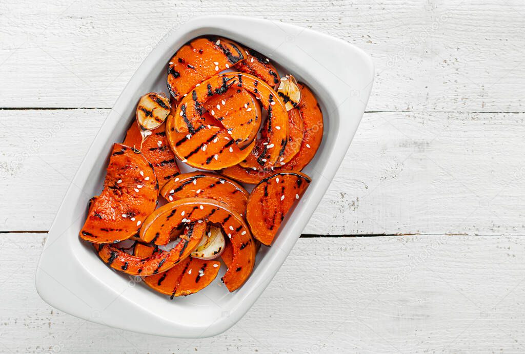 Grilled butternut pumpking slices on white wooden background. Healthy organic dieting food. Top view