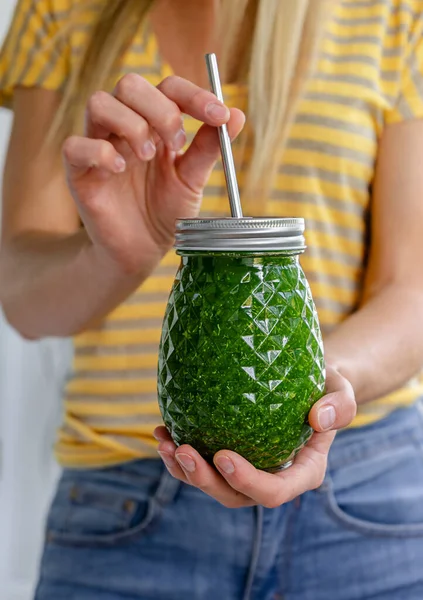 Kadın elleri detoks smoothie kavanozunu çevreci metal pipetle tutuyor. Kilo verme konsepti.