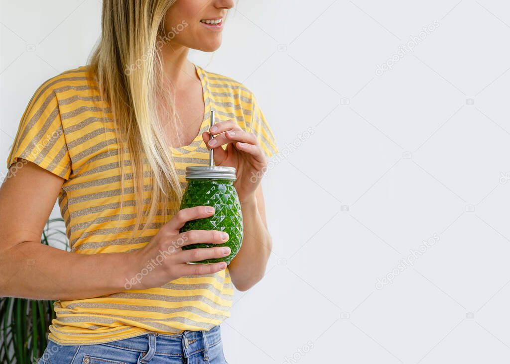 Cropped portrait of smiling woman with green vegetable smoothie jar. Detox diet concept.
