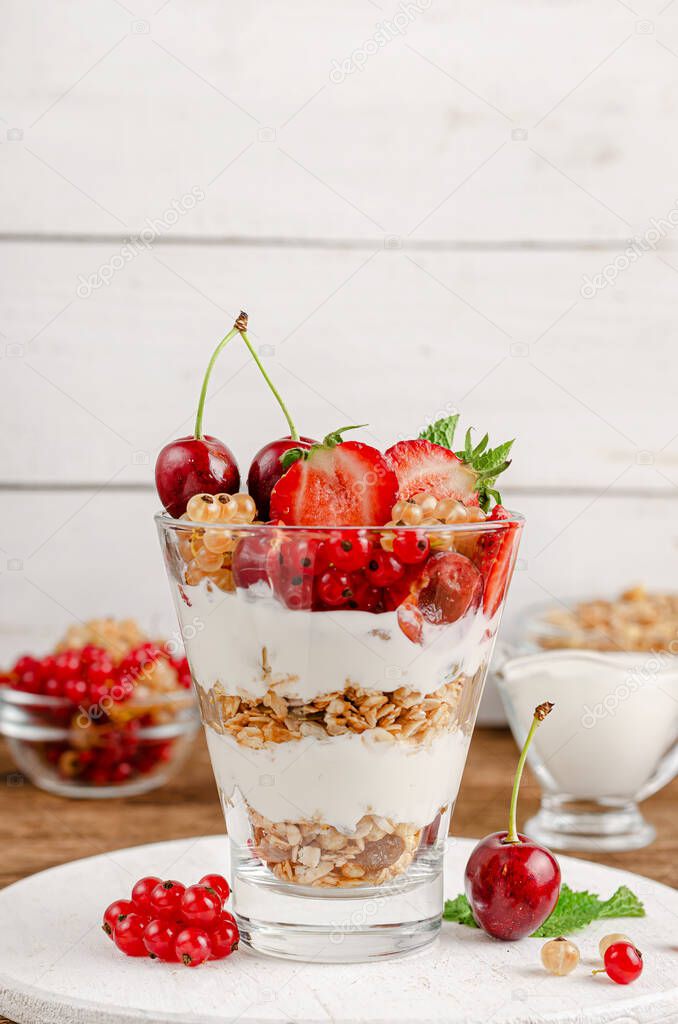 Healthy dessert of granola with yogurt and fresh berries on white wooden background. Copy space
