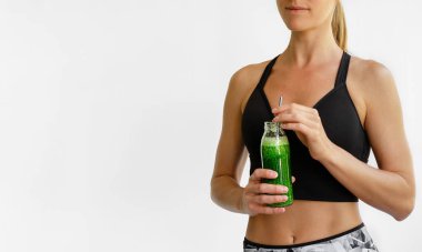 Yeşil smoothie şişesi tutan beyaz bir kadın. Sağlıklı yaşam tarzı kavramı.