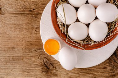 Kırık beyaz yumurta ve ahşap arka planda çiğ yumurta sarısı. Uzayı kopyala, yukarıdan