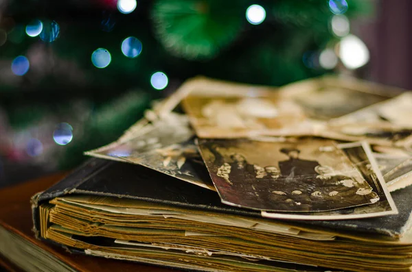 Vintage photo album with family photos on Christmas tree background. Life values and generations traditions concept.