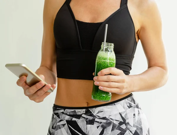 Calorie counting. Slim woman holding a bottle of broccoli and spinach smoothie.