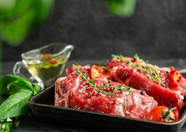 Izgara tavada çiğ biftek, otlar ve baharatlı yağ. Yemek hazırlama konsepti. Boşluğu kopyala