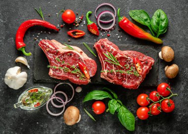 Baharatlı, sebzeli ve koyu arkaplanlı taze dana biftekleri. Düz yatış, üst görünüm