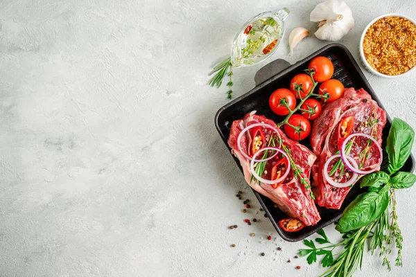 Izgarada taze dana kemiği bifteği, baharatlar ve çimento arka planda bitkiler. Üst görünüm, alanı kopyala