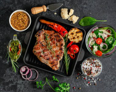 Yemek arkaplanı. Kızarmış domuz bifteği, sebze, baharat ve taze salata. Üst görünüm