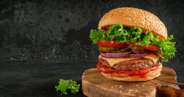Sebzeli hamburger, ketçap, çedar peyniri ve tahta üzerinde salatalık turşusu. Sokak yemeği..