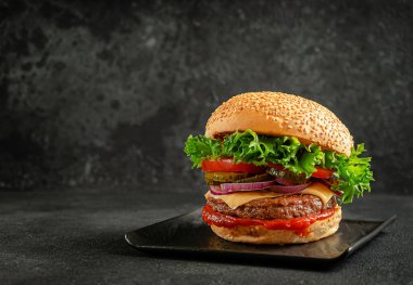 Biftekli ızgara hamburger, soğan, domates, salata, salatalık turşusu ve çedar peyniri. Sokak yemeği..