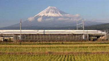Japonya, Honshu, Fuji Dağı, Shinkansen Mermi Treni kar kaplı yanardağın altındaki pirinç tarlalarından geçiyor.