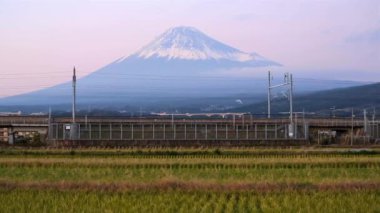 Japonya, Honshu, Fuji Dağı, Shinkansen Mermi Treni kar kaplı yanardağın altındaki pirinç tarlalarından geçiyor.