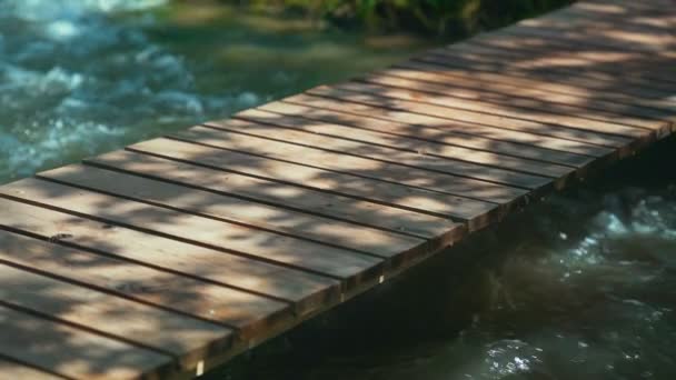 Pequeño puente de madera sobre un río de montaña con piedras. Cámara lenta HD — Vídeo de stock