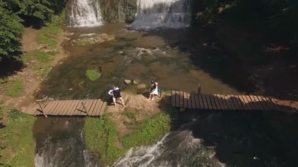 Вид з повітря. Двоє музикантів Піаніст і бандура грають на каменях біля водоспаду — стокове відео