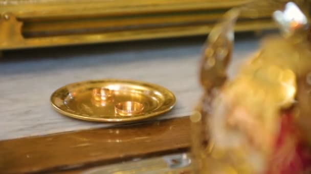 Wedding rings of newlyweds during the consecration of holy water in the church — Stock Video