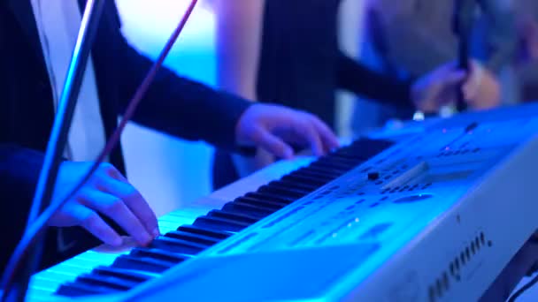 4k Mani maschili che suonano il pianoforte elettrico sotto l'illuminazione colorata del palco, primo piano — Video Stock