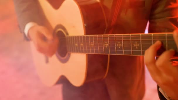 Guitarrista 4k toca la guitarra acústica en el escenario del club nocturno, destellos de luces de color — Vídeos de Stock