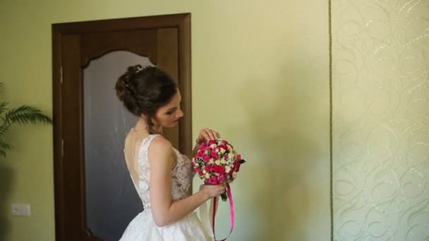 Mooie bruid in witte bruiloft neglige vasthouden en knuffelen trouwjurk — Stockvideo