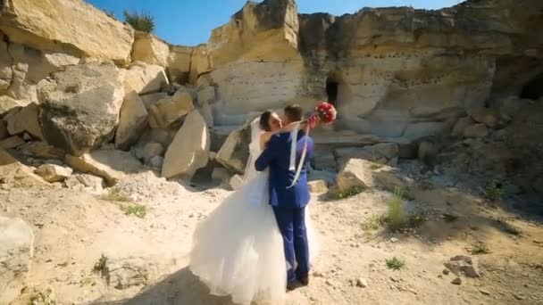 Mariée et beau marié marchant près des rochers sablonneux — Video